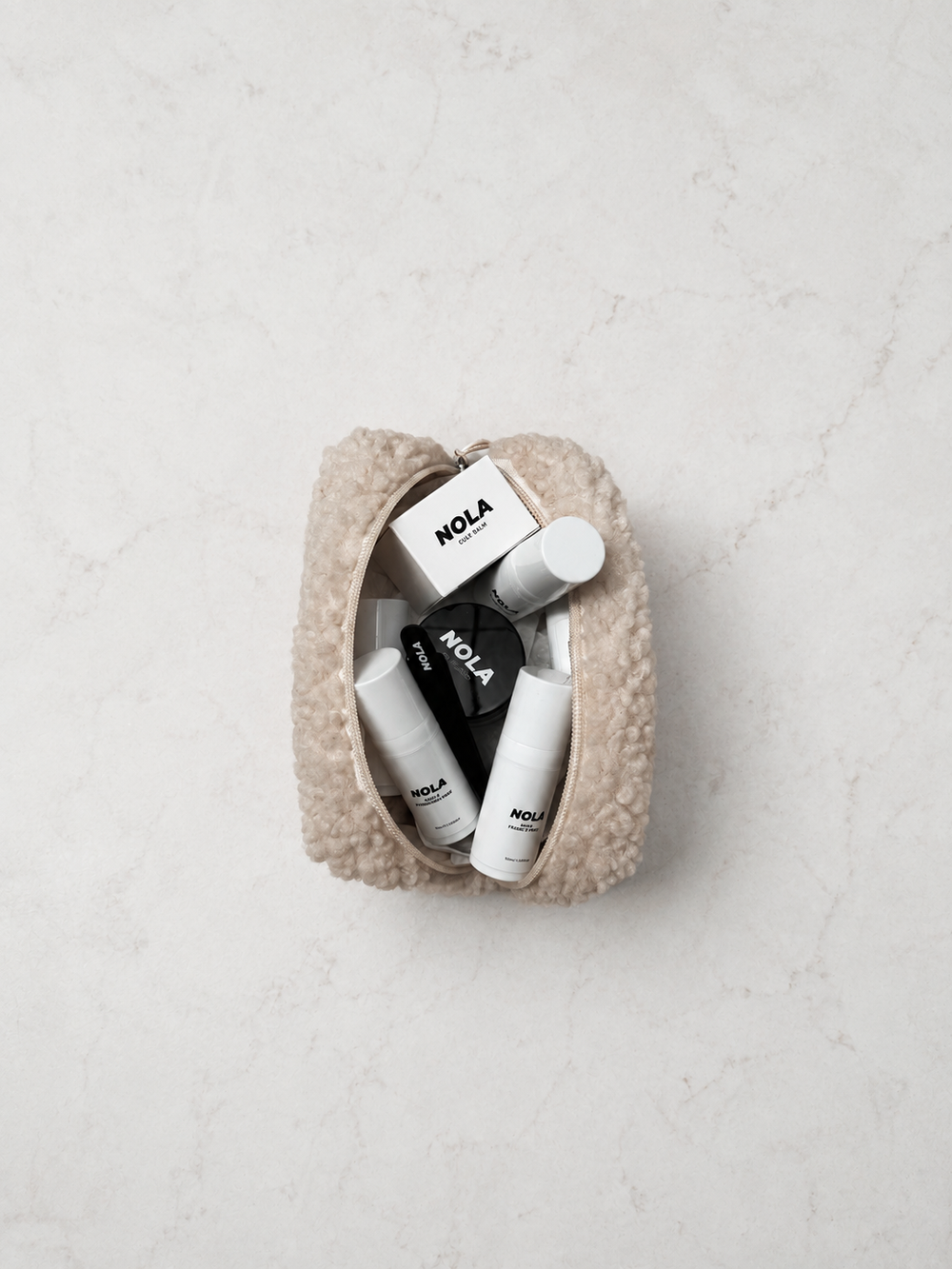NOLA products arranged in a beauty pouch